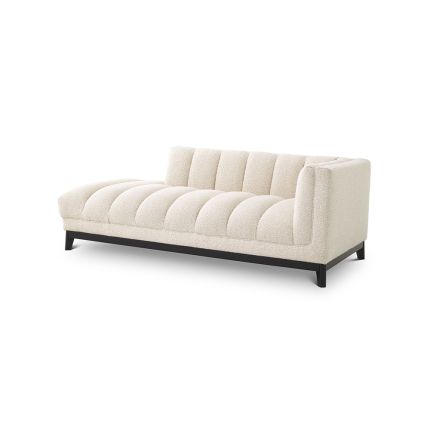 A luxurious lounge sofa by Eichholtz with a bouclé cream upholstery, deep channel stitching and a black base