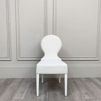 A white linen dining chair with white wooden feet 
