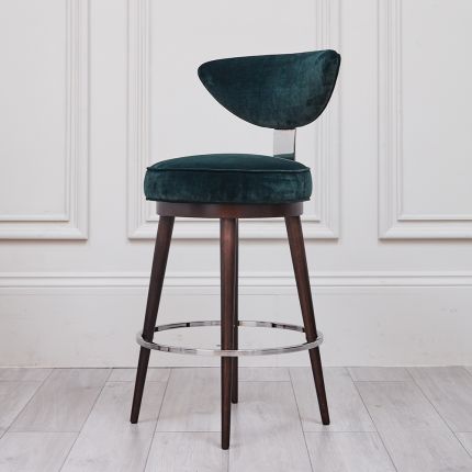 A luxurious, upholstered bar stool with tapered legs and silver accents