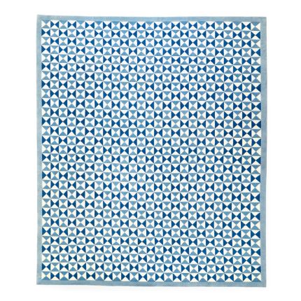 A hand-woven wool and viscose rug by Jonathan Adler with an iconic blue toned 60s inspired bowtie design 