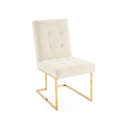 A boucle upholstered dining chair on a brass frame.
