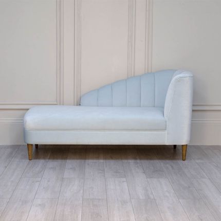 A curvaceous chaise longue with a pale blue velvet upholstery and seashell-like frame 