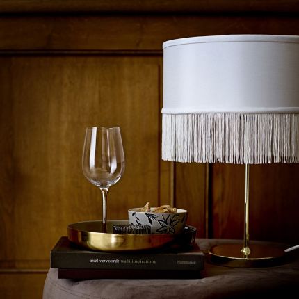 a fabulous golden table lamp with a tasselled white lampshade