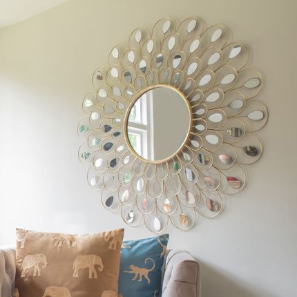 A glamorous wall mirror with a peacock tail feather design and champagne gold finish
