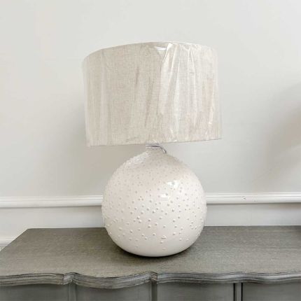Textured circular base lamp with wobbly linen shade