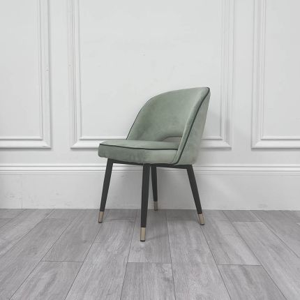 Pistachio green velvet dining chair with faux leather piping and gold caps on black frame