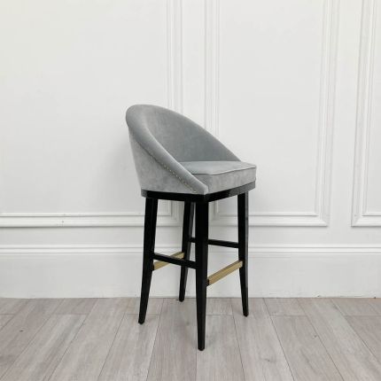 A sumptuous bar stool with a luxurious velvet upholstery and glossy lacquered legs