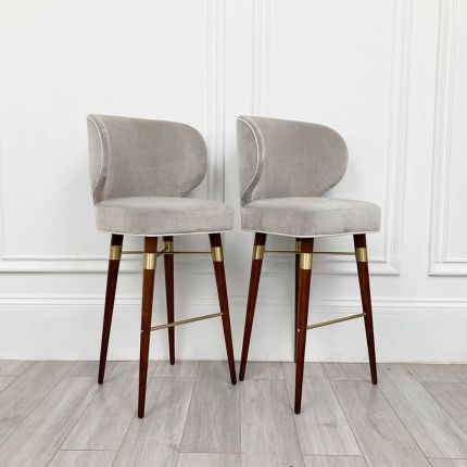 An art deco-inspired bar chair with velvet upholstery walnut legs and brass details.