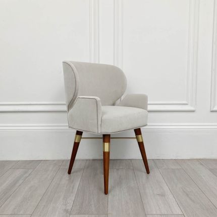 Ultra-stylish grey velvet dining chair with brass accents and rich wooden legs