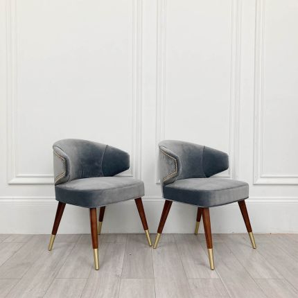 A sumptuous blue-grey velvet dining chair with hand-applied studs
