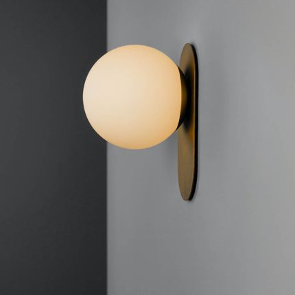 A luxury wall sconce by Schwung with a brushed brass finish and a glamorous detailed clear glass bulb