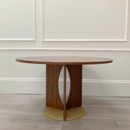 Round wooden dining table with lightly scratched brass base
