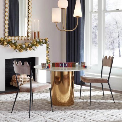 A glamorous dining table by Jonathan Adler with a brass base and marble top