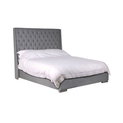A gorgeous grey linen upholstered bed with deep-buttoned details and silver studding