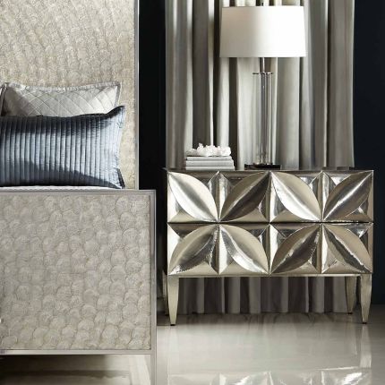 A radiant bedside table by Bernhardt featuring two carved floral patterned push to open doors and a white interior finish