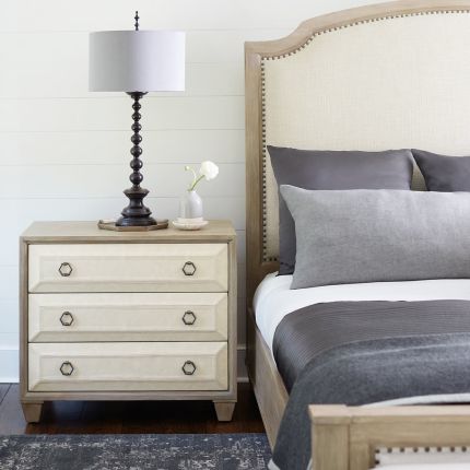 A stylish natural wood bedside table with performance fabric and tarnished nickel handles 