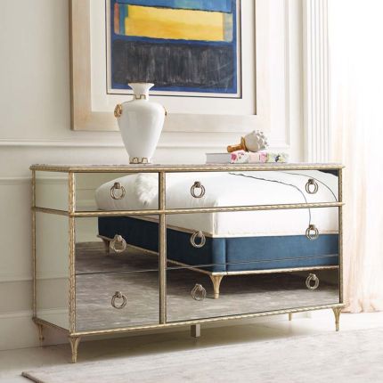 A luxurious mirrored dresser/chest of drawers with antique detailing and a champagne finish