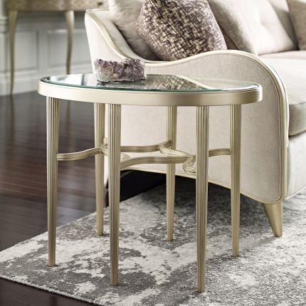 A contemporary end table by Caracole with a curved design and champagne finish