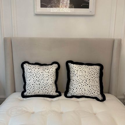 A glamorous black and white cushion with black fringing