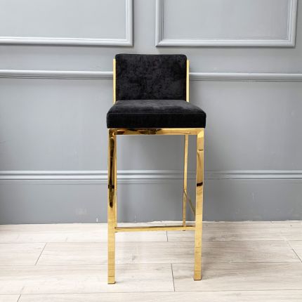 A chic gold barstool with black velvet upholstery