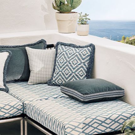 A chevron patterned outdoor cushion with a matching fringe 
