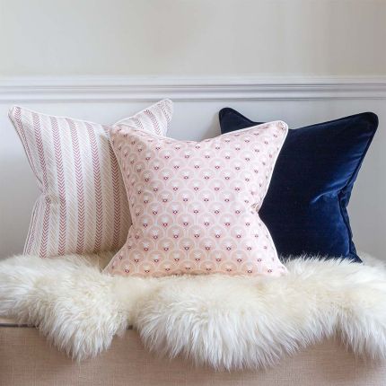 A baby pink cushion with pink and white floral motifs