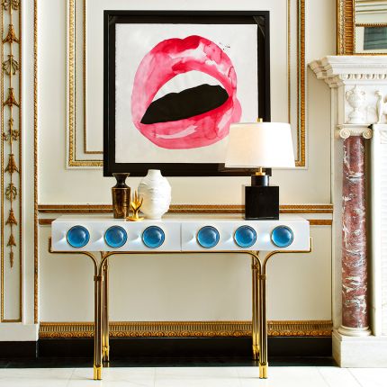 A futuristic white console table with blue acrylic cabochons and a polished brass base 