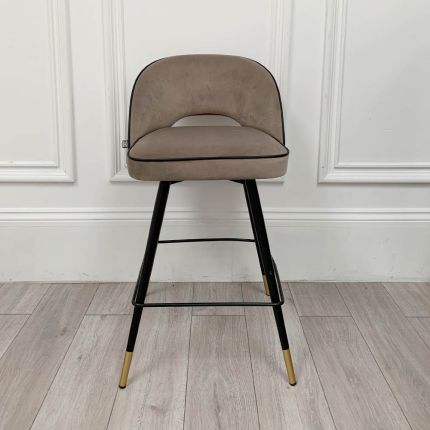Sleek greige stool with tapered black legs and brass details