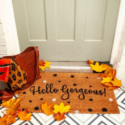 A chic polka dot coir doormat with cursive text 'hello gorgeous' 