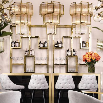 A luxurious chandelier by Eichholtz with a curved antique brass finish and decorative clear glass rods
