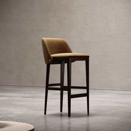A luxurious armchair featured in suede upholstery with beech wood legs and stainless steel accents