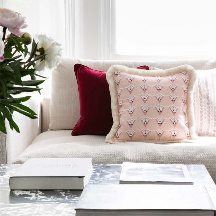 A stunning pink cushion with delicate white fringing