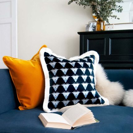 A lavish, art deco inspired, dark blue cushion with a white silky fringe