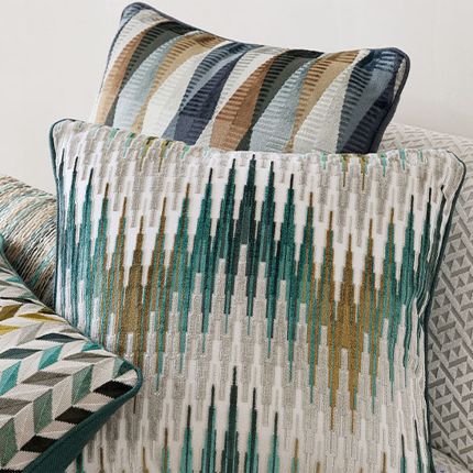 A velvet and linen cushion with a dark green and copper chevron pattern.