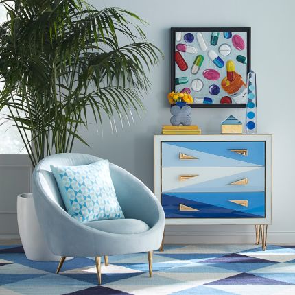 A stylish, modern armchair with light blue velvet upholstery and polished brass legs 