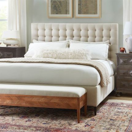 A modern bed with a soft and padded, deep buttoned back and upholstered cream finish 
