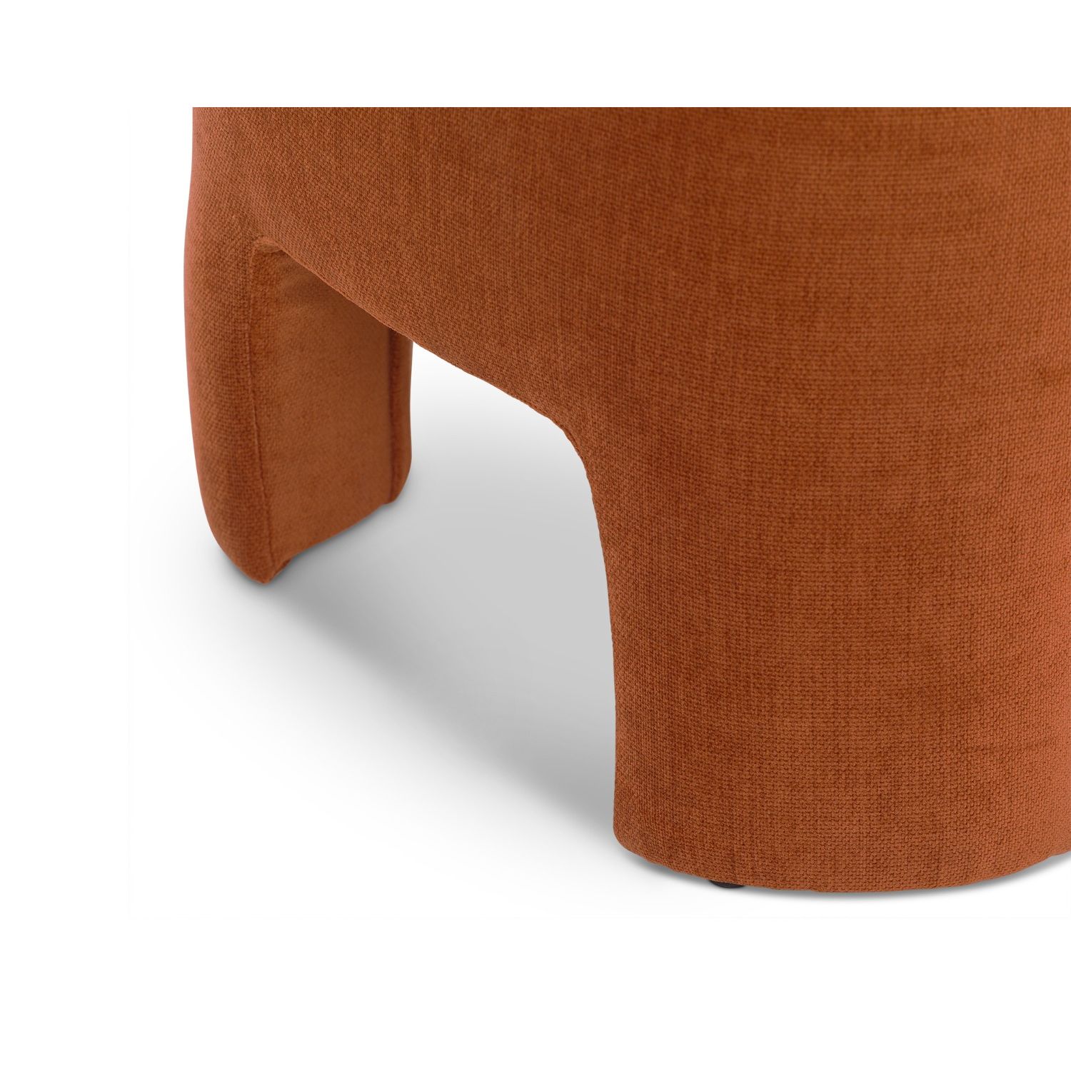 Rounded silhouette footstool with short, wide legs upholstered in rust coloured fabric