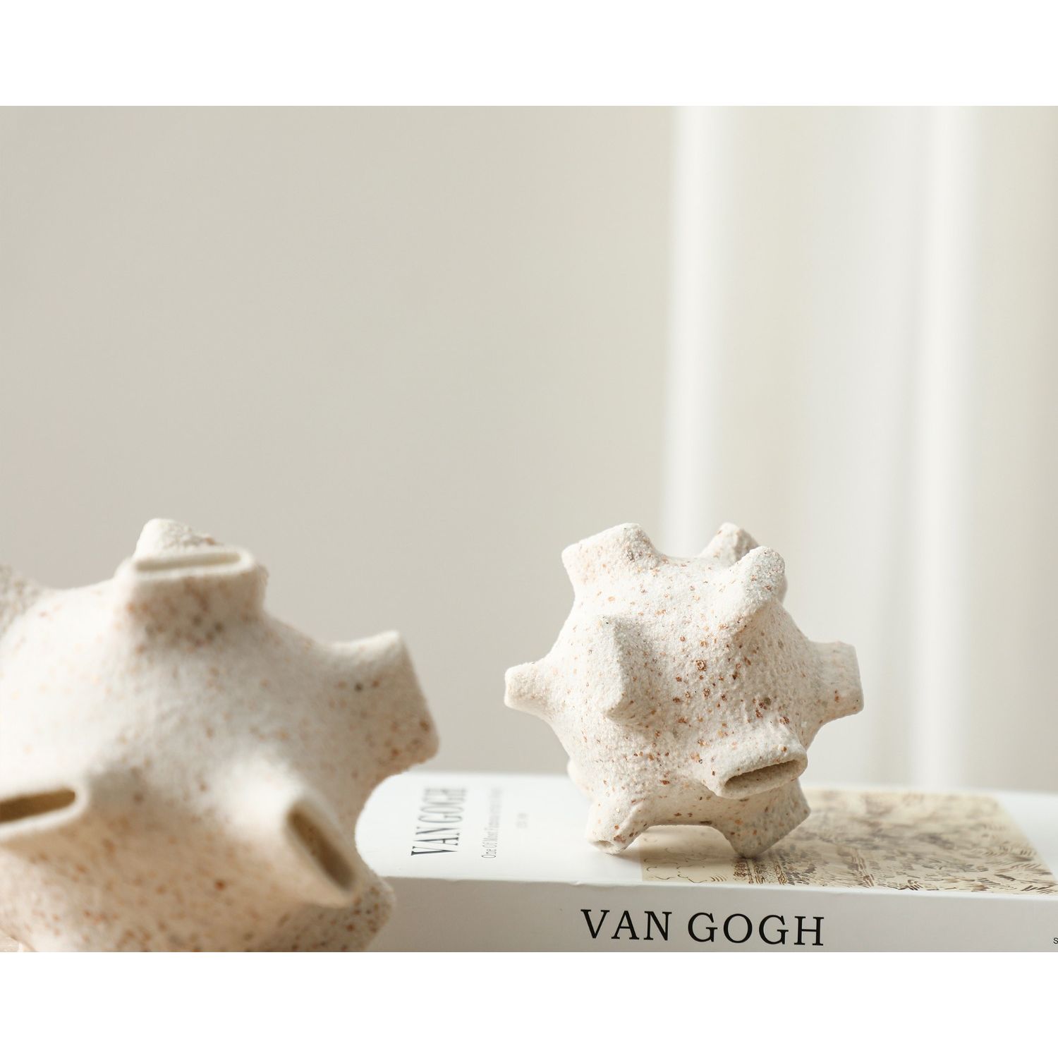White sculpture with terracotta-coloured speckles and narrow craters