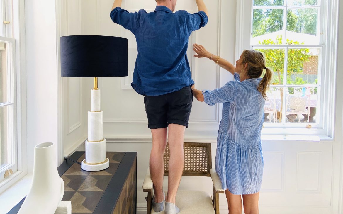 a man and a women putting up wall art